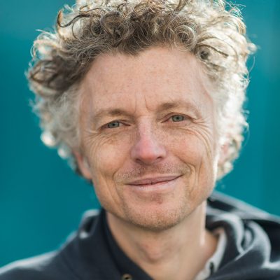 Headshot of Billy: a tall, slim, white man in his fifties with curly hair.