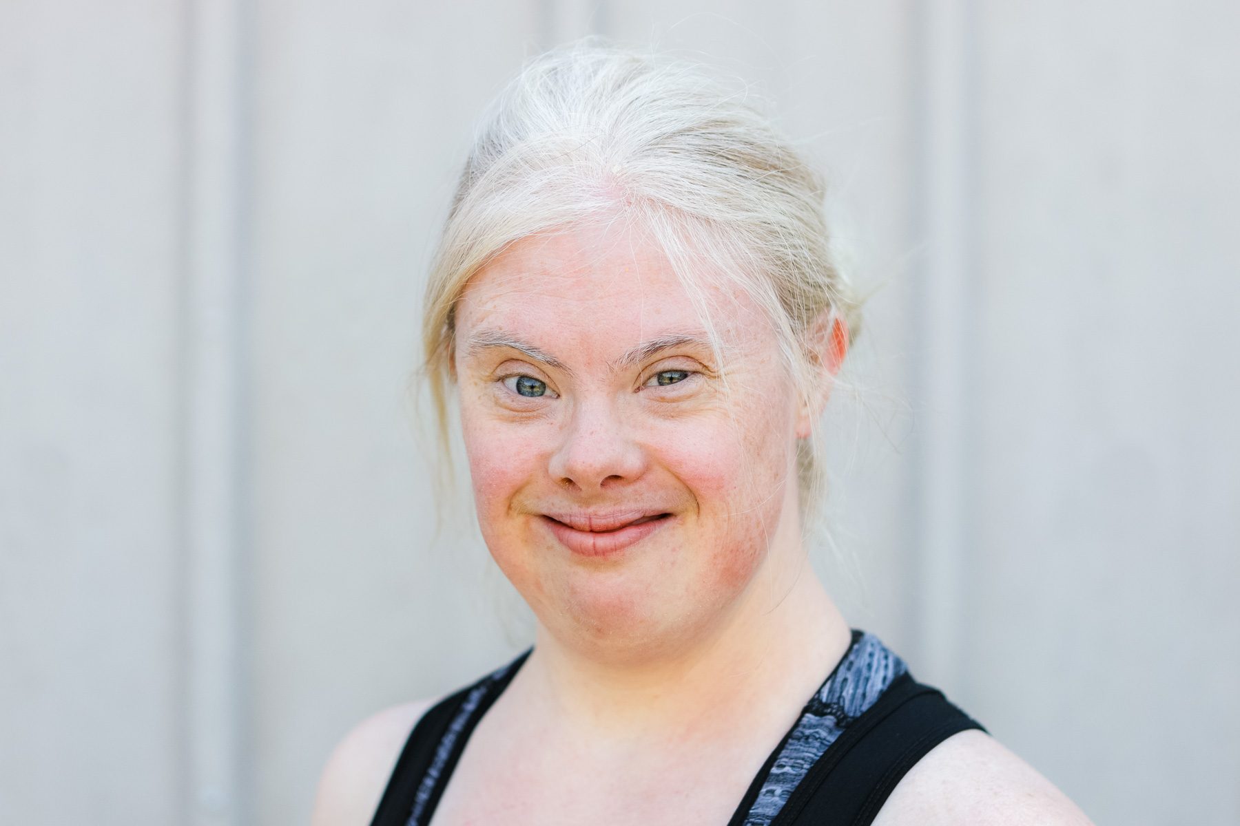 Helen poses for the camera. She is a young white woman with bleached blonde hair tied back. She has bright blue eyes and is wearing a sporty sleeveless top.