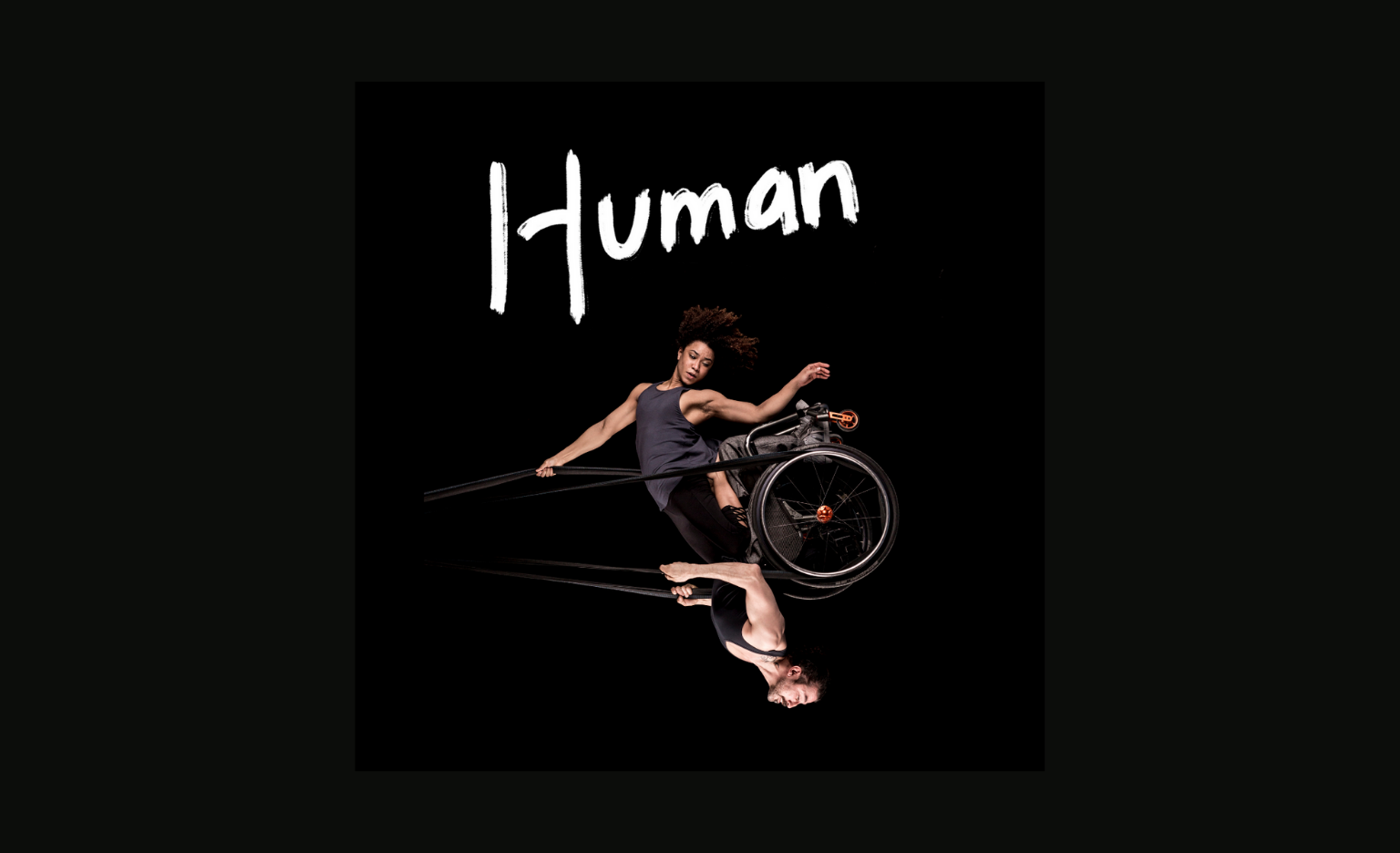 Black background. A photo of a woman and a man swinging in the air like a pendulum, looking powerful and graceful. They share a wheelchair which is held up in the air by black circus straps. She has frizzy brown hair, muscular arms and wears a grey tank top She is sitting on knees on his thighs and one of her arms holds the straps above her head while the other points down towards the floor. He has a neatly trimmed brown beard, muscular arms and wears a black tank top. He holds the straps to the sides of his chest with both hands. The image captures them at the highest point of the swing, to our right, bringing the man to an upside-down position with the woman above him. Their bodies are doing something hard, but their strength makes it look effortless. One word written in white, thick, brush-style letters to the right of the photo: 'Human'.