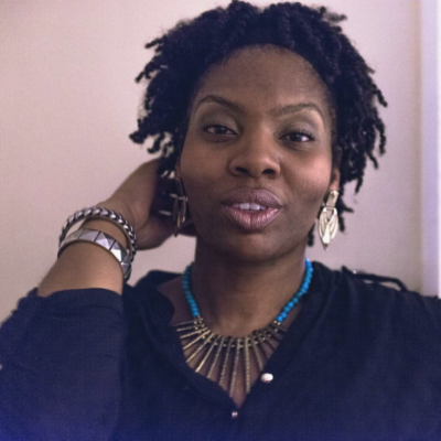 Headshot of Vicki, a black woman with short, dark brown hair, brown eyes. She is wearing gold dangly earrings and a black loose shirt.