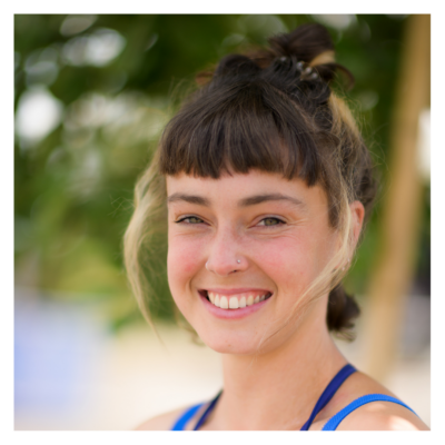 Tilly: a white woman in her twenties with shoulder-length brown hair tied up and a stud on the right side of her nose. She is smiling brightly at the camera.
